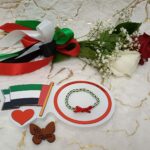 Handmade bracelet of black, white and green beads with red ribbon .