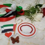 Handmade bracelet of red beads and simile faces by UAE flag colors.
