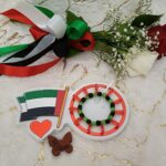 Handmade bracelet of black and green beads with red heart shaped beads and a white ribbon .